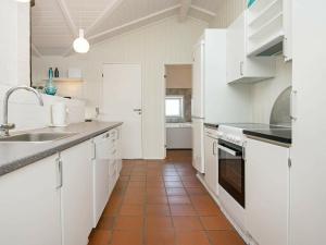 瓦伊厄斯斯特兰德8 person holiday home in Vejers Strand的厨房配有白色橱柜和瓷砖地板。