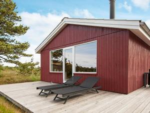 博利尔马克Three-Bedroom Holiday home in Rømø 35的一座红色的建筑,甲板上设有长凳