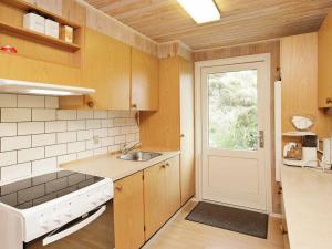 亨讷斯特兰德5 person holiday home in Henne的厨房配有木制橱柜、水槽和门