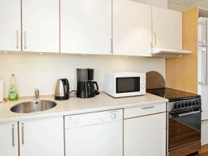 瓦伊厄斯斯特兰德4 person holiday home in Vejers Strand的厨房配有白色橱柜、水槽和微波炉