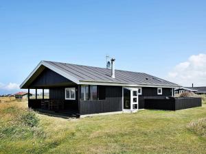 伦斯楚普Three-Bedroom Holiday home in Hjørring 25的坐在草地顶上的黑色房子