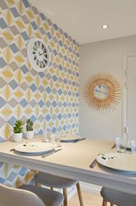 图尔昆LocationsTourcoing - Le Famelart的用餐室配有桌椅和墙上的时钟