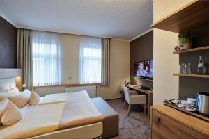 盖尔森基兴祖姆施万安姆比恩特酒店的酒店客房配有一张床、一张书桌和一台电视。