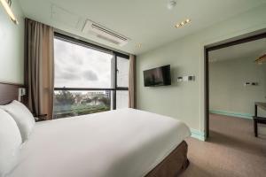 西归浦市Sunrise Hotel Jungmun Branch的卧室设有一张白色大床和大窗户
