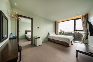 西归浦市Sunrise Hotel Jungmun Branch的一间卧室设有两张床和大窗户