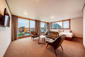 西归浦市Sunrise Hotel Seongsan的酒店客房配有一张床、一张沙发和椅子。