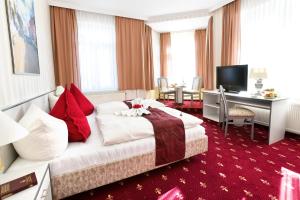 梅拉内Parkhotel Meerane的酒店客房设有一张大床和一张书桌。