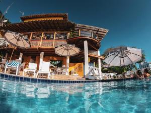 莫罗圣保罗Passárgada Pousada e Restaurante的一个带椅子和遮阳伞的游泳池的度假酒店