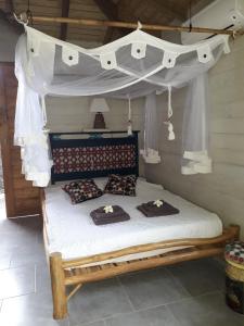 勒穆莱The BlueBamboo的一间卧室配有一张带天蓬和枕头的床