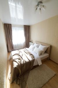索利戈尔斯克PaulMarie Apartments on Molodeznaya的一间卧室配有一张带白色床单的床和一扇窗户。