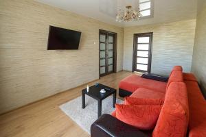 索利戈尔斯克PaulMarie Apartments on Molodeznaya的客厅配有红色沙发和平面电视