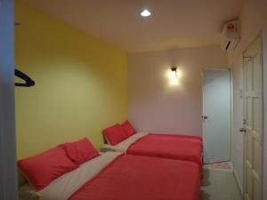 马六甲法摩萨2号民宿的配有红色和白色床单的客房内的两张床