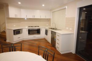 墨尔本Silver House - Melbourne Airport Accommodation的厨房配有白色橱柜和炉灶烤箱。