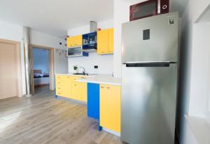 Dugo SeloApartman GRC的厨房配有黄色橱柜和不锈钢冰箱