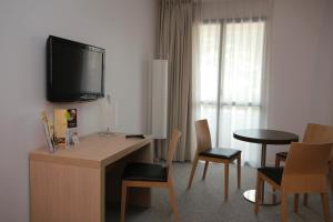 尼斯艾萨帝都酒店的酒店客房设有一张桌子,墙上配有电视。
