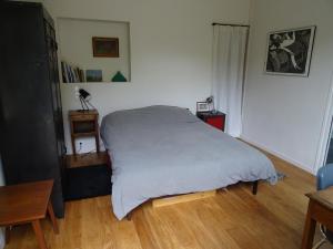 凯恩Chambre d'hôtes sur jardin acces PMR的卧室配有白色的床,铺有木地板