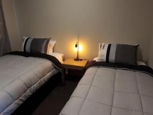 因弗卡吉尔South City Accommodation Unit 1的一张桌子上灯的房间里两张床铺
