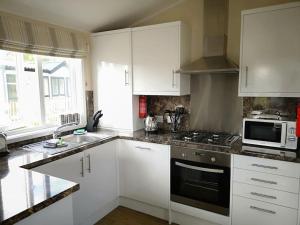 维斯贝希Carnoustie Lodge的厨房配有白色橱柜和炉灶烤箱。