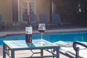 斯泰伦博斯Lyngrove Wines & Guesthouse的一瓶葡萄酒和一杯池畔餐桌上的酒