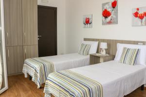 乌真托B&B Incanto Salento的两张位于酒店客房的床,墙上挂着红色鲜花
