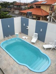 弗洛里亚诺波利斯Casa com Piscina temporada的一个带两把椅子的庭院里的一个大型游泳池