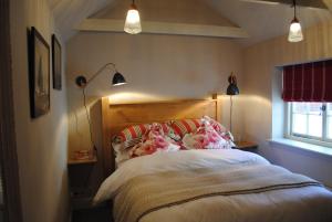 利明顿Courtyard Cottages Lymington, 2 Adults only的一间卧室配有一张床、两盏灯和一个窗户。