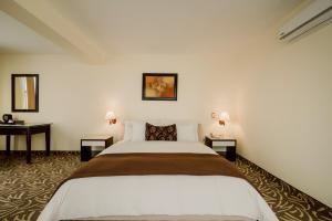 利马贵族酒店的一间卧室配有一张大床和两张桌子