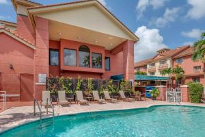 棕榈滩花园温莎花园贝斯特韦斯特PLUS套房/会议中心酒店的一座带椅子的游泳池以及一座建筑