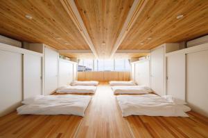 Motoshin渚泊魚津丸的木天花板的房间里一排床铺