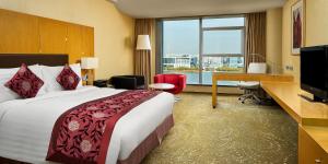 天津天津滨海圣光皇冠假日酒店的酒店客房配有一张床、一张书桌和一台电脑