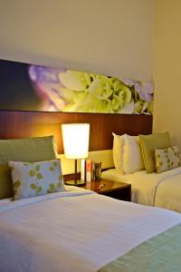 吉隆坡Somerset Kuala Lumpur的酒店客房设有两张床,墙上挂有绘画作品