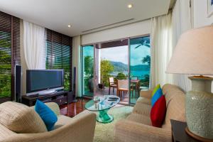 卡塔海滩Kata gardens penthouse seaview with rooftop pool 8C的客厅配有电视、沙发和桌子