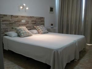 阿雷西费Hostal Residencia Cardona的卧室配有一张带白色床单和枕头的大床。