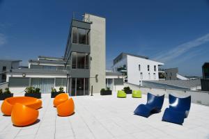 波尔多Appart-Hôtel Mer & Golf City Bordeaux Bassins à flot的一群橙色和蓝色的椅子,在一座建筑前