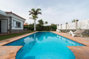 马斯帕洛马斯Villa Cosmos chalet con gran piscina y jardin privado的一座房子前面的蓝色海水游泳池