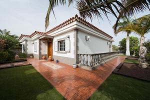 马斯帕洛马斯Villa Cosmos chalet con gran piscina y jardin privado的棕榈树白色的小房子