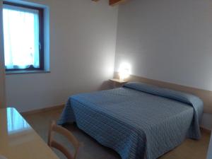 维罗纳Agriturismo Corte Maccini的一间卧室配有一张床、一张桌子和一个窗户。