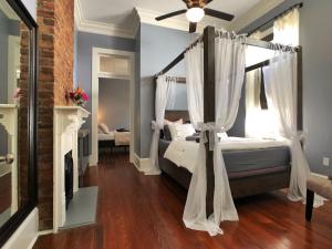 新奥尔良Luxury Historic Shotgun Home in Lower Garden District的一间卧室设有一张天蓬床和一个壁炉