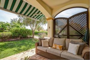 卡武埃鲁2bedroom bungalow on Gramacho Golf Resort heated shared pool的一张沙发,坐在带拱门的庭院