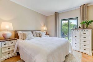 卡武埃鲁2bedroom bungalow on Gramacho Golf Resort heated shared pool的白色的卧室设有一张大床和一个窗户