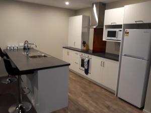 因弗卡吉尔South City Accommodation unit 3的厨房配有白色橱柜和白色冰箱。