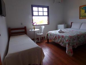 阿拉鲁阿马Kazaya Pousada的一间卧室设有两张床、一张桌子和一个窗口