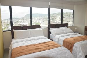 埃斯梅拉达斯Olan´s Hotel Group的带大窗户的客房内的两张床