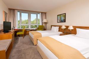 科隆科隆波恩机场莱昂纳多酒店的酒店客房设有两张床、一张桌子和一台电视。