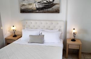 菲罗斯特法尼米洛奥斯酒店的一间卧室配有一张白色的床,桌子上配有两盏灯