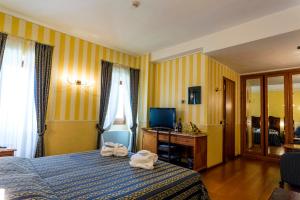 索亚诺德拉戈Hotel Porta Del Sole的酒店客房,配有带毛巾的床
