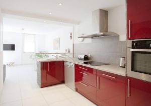 邦多勒Au cœur de la ville的一间铺有白色地板并配有红色橱柜的厨房
