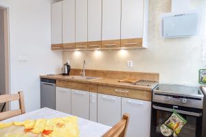 什切青Apartament Yooka的厨房配有白色橱柜、桌子和水槽。