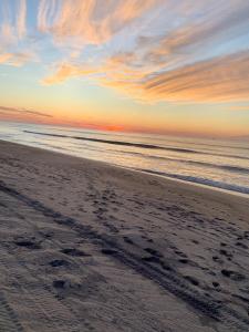 阿默甘西特海洋海景度假村酒店的沙滩上的日落,沙滩上留下了脚印