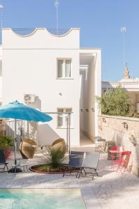 苏尔博Salento Rosa dei Venti的一个带椅子和遮阳伞的庭院和一个游泳池